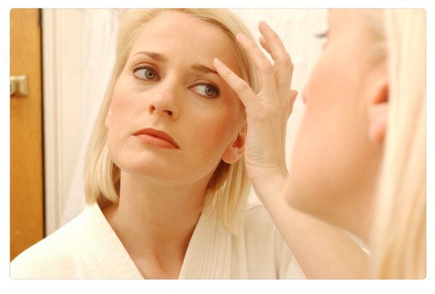 Woman looking at her reflection to show the myths about wrinkle reduction. 